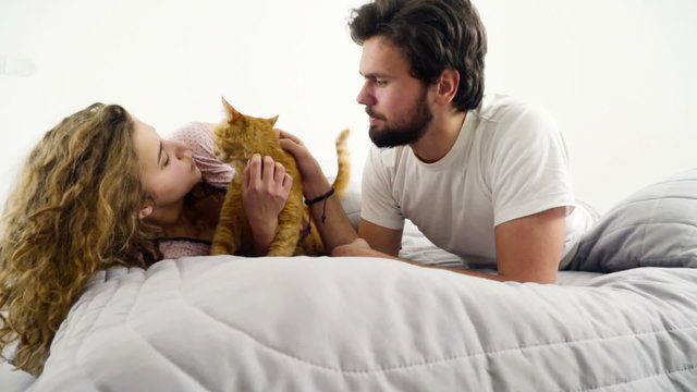 couple in bed caressing a ginger cat slow motion
