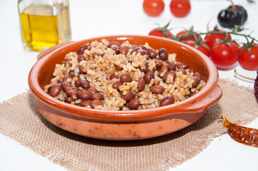 Cazuela de arroz con alubias y varios ingredientes sobre un mantel de rafia