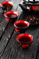 Cups of tea and teapot on black wooden table