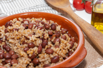 Cazuela de arroz con alubias y varios ingredientes sobre un mantel de rafia