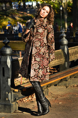 Young brunette model in elegant coat posing at Central Park New York location for fall fashion photo shoot.
