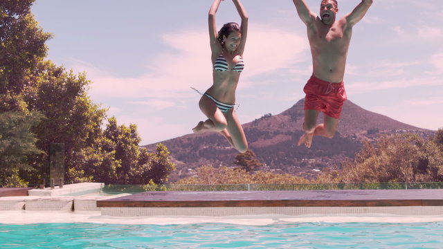 Happy couple jumping in the swimming pool