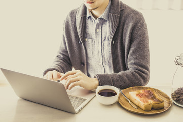 朝食を食べながらデスクワークをしているアジア人男性