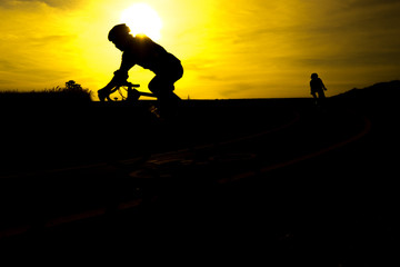 Friends on bicycles outdoors against sunset. Silhouette