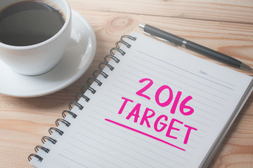 closeup of a notebook with text written in it and a cup of coffee on a wood table