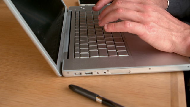 Businessmans hands typing on laptop keyboard