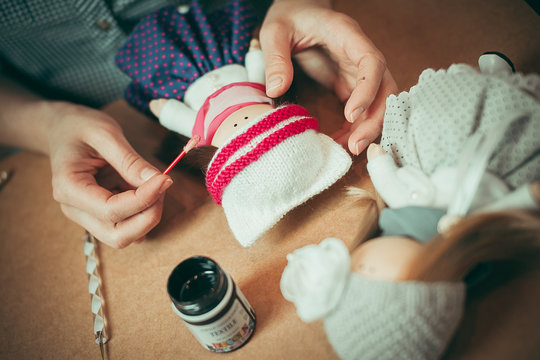 Young woman is making a doll.