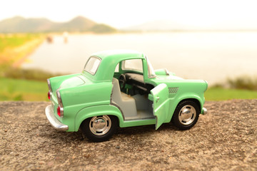 Green toy car park on road at riverside