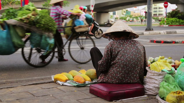 Vendor woman sitting and selling fruits on heavy hanoi traffic