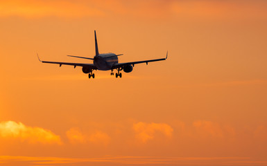 Fototapeta na wymiar Airplane landing on sunset