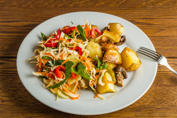 Fried potato and fresh salad on the plate 