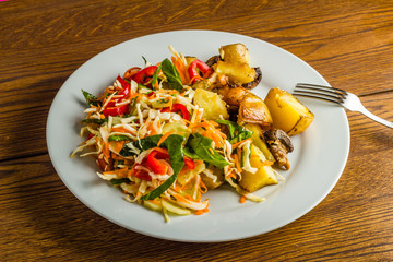 Fried potato and fresh salad on the plate 