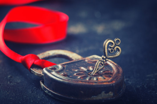 Padlock with key and a red ribbon ,the symbol of love.The background to the Valentine's day.Toned image.Vintage style.selective focus.