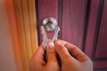Hand hold two key with blurred door background,choose the right