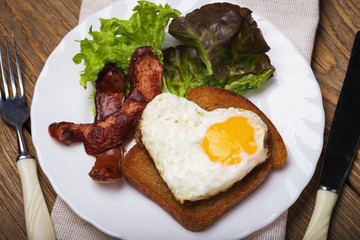Scrambled eggs with heart shaped sausage for breakfast