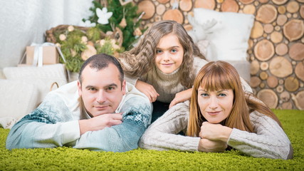 family of mother, father and daughter. Happy Family With Child Laying On Carpet At Home. Spend time relaxing together.