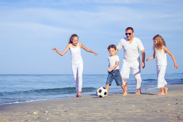 Father and children playing on the beach at the day time.