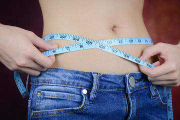 slim woman measuring body, wearing jeans