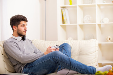 Fototapeta premium Young guy enjoying computer game, playing with joystick, smiling 