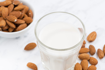 almond milk in a glass on white table, top view, selective focus