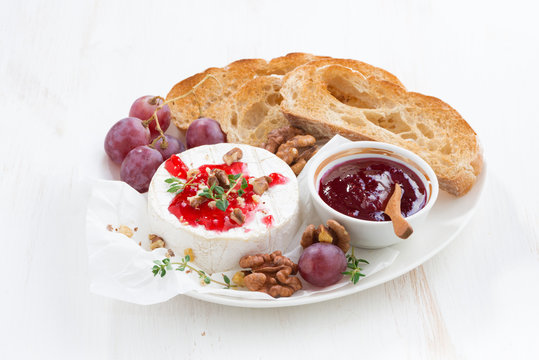 camembert with berry jam and toast on a white wooden background