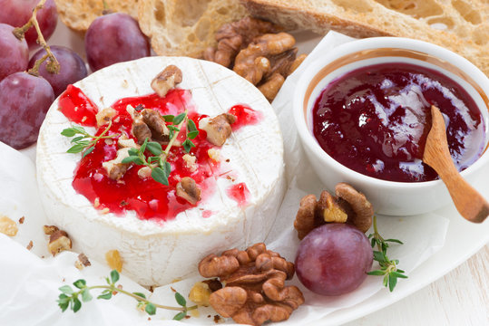 camembert with berry jam and toasts on plate, close-up