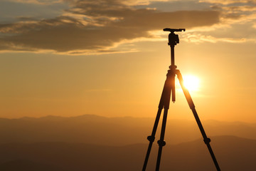 Silhouette from a recording camera on a tripod during sunrise