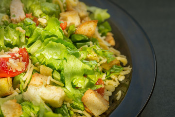 Caesar salad made of fresh vegetables on dark background. Selective focus.