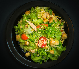 Caesar salad made of fresh vegetables on dark background. Selective focus.