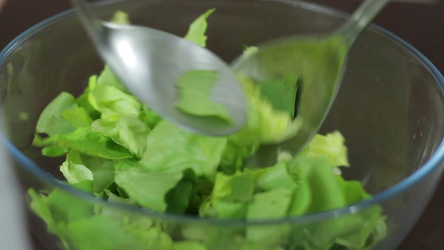 Preparation of fresh salad, mixing in the bowl, close up
