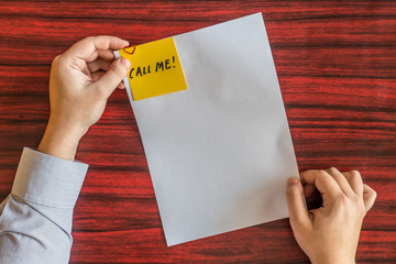Obraz premium Hands holding blank page with yellow note attached by heart shaped paper clip.