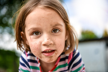 Little kid with dirty face from playing outside in the dirt and