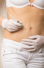 Closeup of a slim girl's hands as she gives herself a shot. She holding a syringe