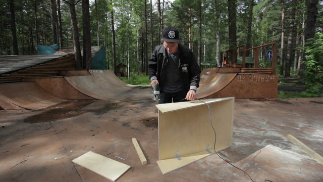 man sawing wood products in skatepark
