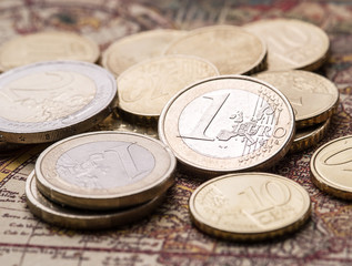 Euro coins over the old world map.