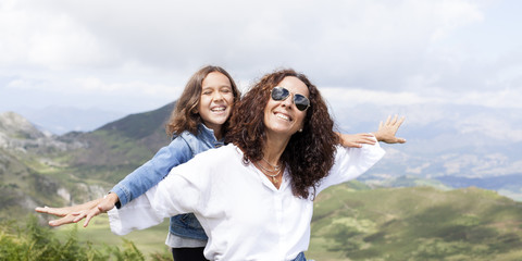 Madre e hija sonriendo al sol en la montaña