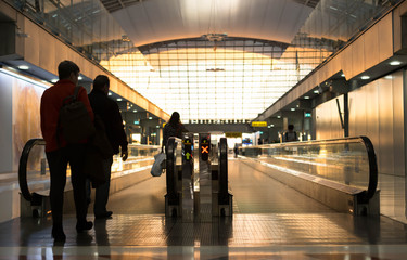 Naklejka premium Silhouettes passengers walk toward escalator in the aieport