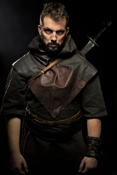 Viking warrior, male dressed in Barbarian style with sword, bear
