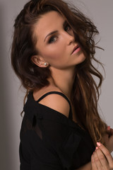 Naklejka premium Woman with beauty long curly brown hair posing at studio