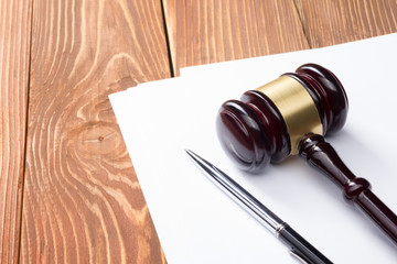 Law book with wooden judges gavel on table in a courtroom or law enforcement office.
