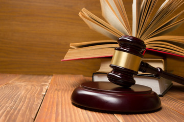 Law book with wooden judges gavel on table in a courtroom or law enforcement office.