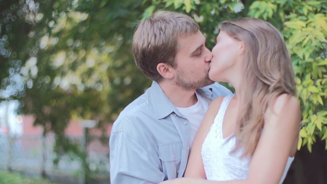 Beautiful young couple kissing and embracing in the park