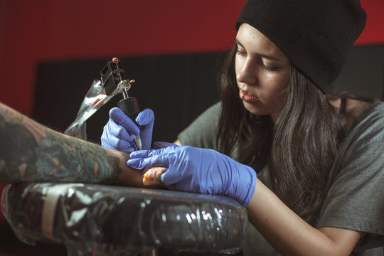 Beautiful brunette girl makes tattoo. Tattooist makes a tattoo. Closeup