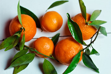 Beautiful ripe tangerines with leaves on white wooden table