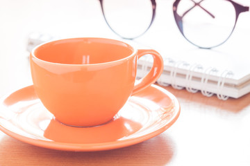 Close up of coffee cup with book and eyeglasses