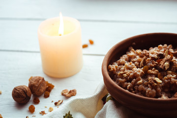 Christmas porridge with candles on white wooden background