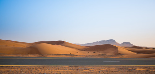 Fototapeta na wymiar desert, sand dunes and the road in the evening