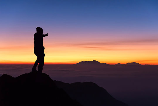 silhouette of man standing and thumbs up on the top of mountain © chanwitohm