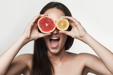 Funny image of young woman holding grapefruit and lemon