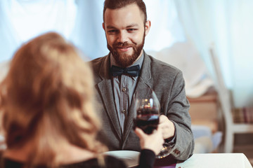 Beautiful young couple with glasses of red wine in luxury restaurant